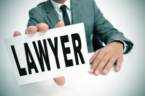 a man wearing a suit sitting in a desk holding a signboard with the word lawyer written in it